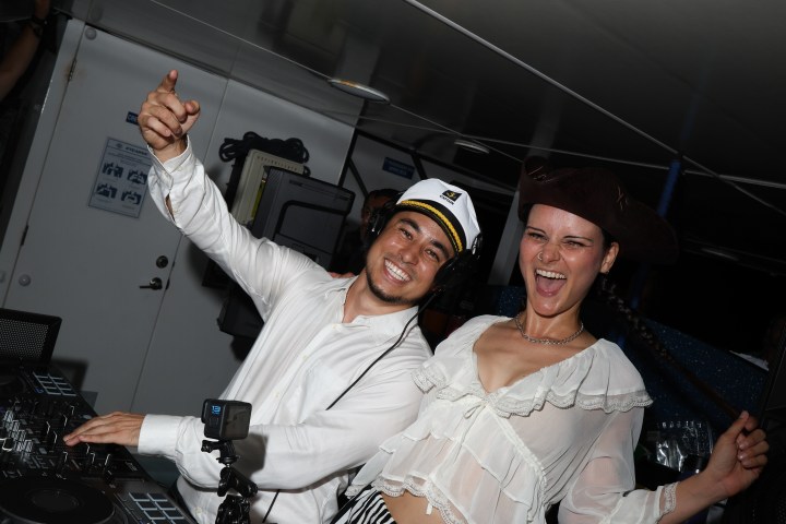 Two people dancing on a boat, one in a captain's hat, the other in a pirate hat.